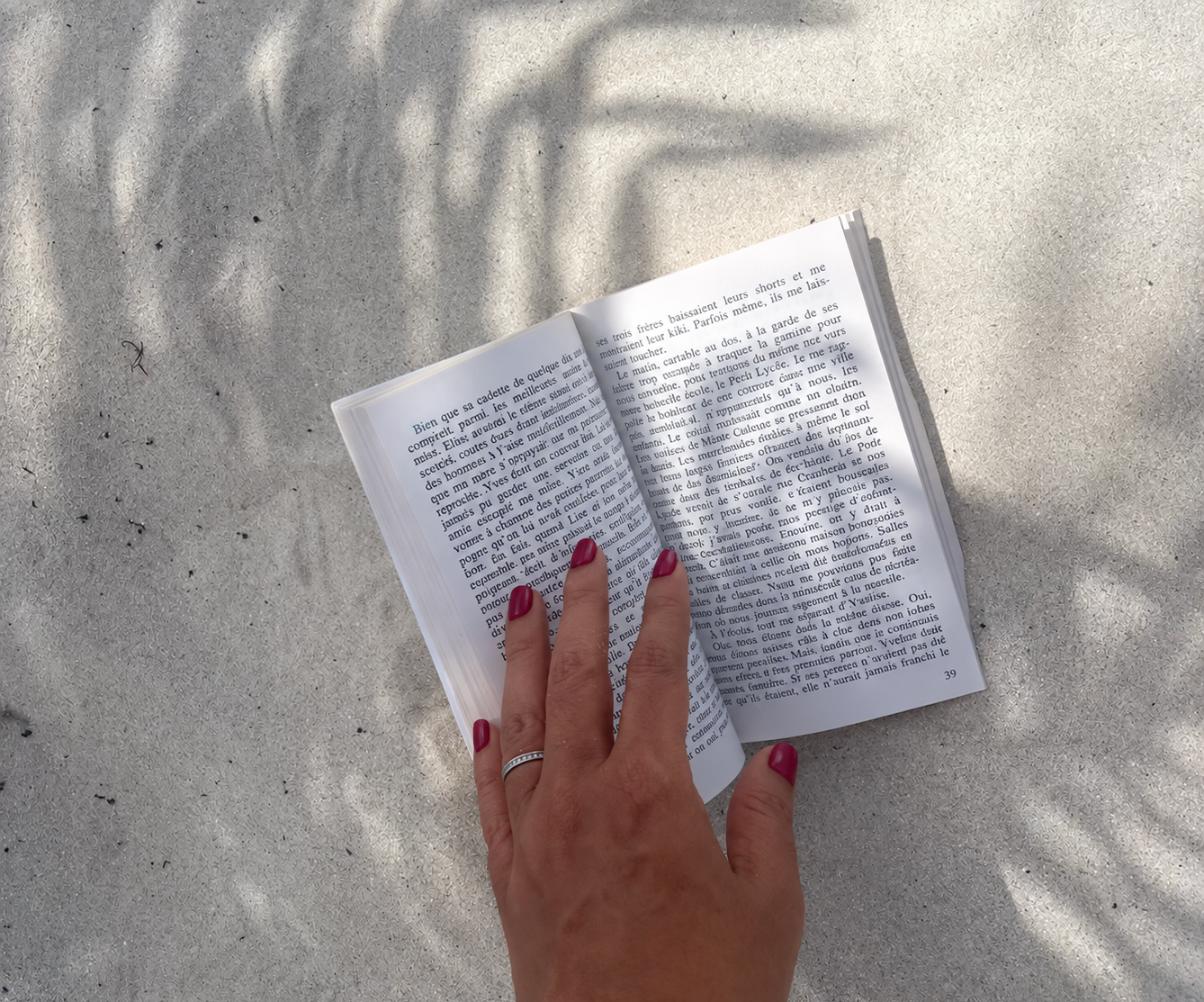 Une main posée sur un livre ouvert sur le sable en guise de couverture pour ma sélection de 8 titres pour la rentrée littéraire.